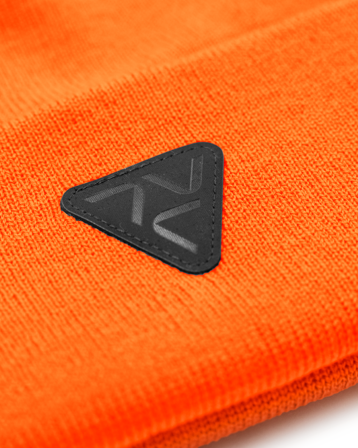 Close-up of Vohl Hi Vis Beanie in Safety Orange showing black triangular logo patch and knit texture - SKU AC-BN-200-OS | color:Safety Orange