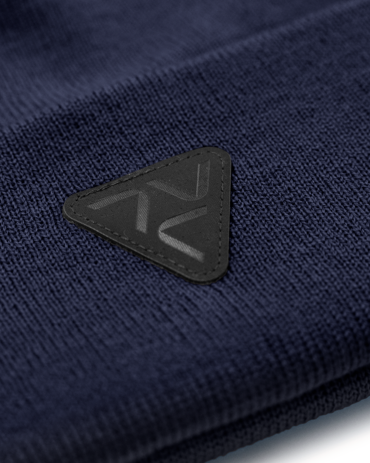 Close-up of Vohl Beanie in Detroit Blue showing black triangular logo patch and knit texture - SKU AC-BN-600-OS | color:Detroit Blue