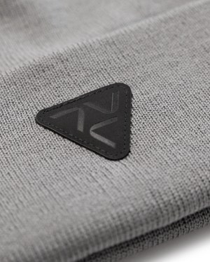 Close-up of Vohl Beanie in Pewter showing black triangular logo patch and knit texture - SKU AC-BN-700-OS | color:Pewter