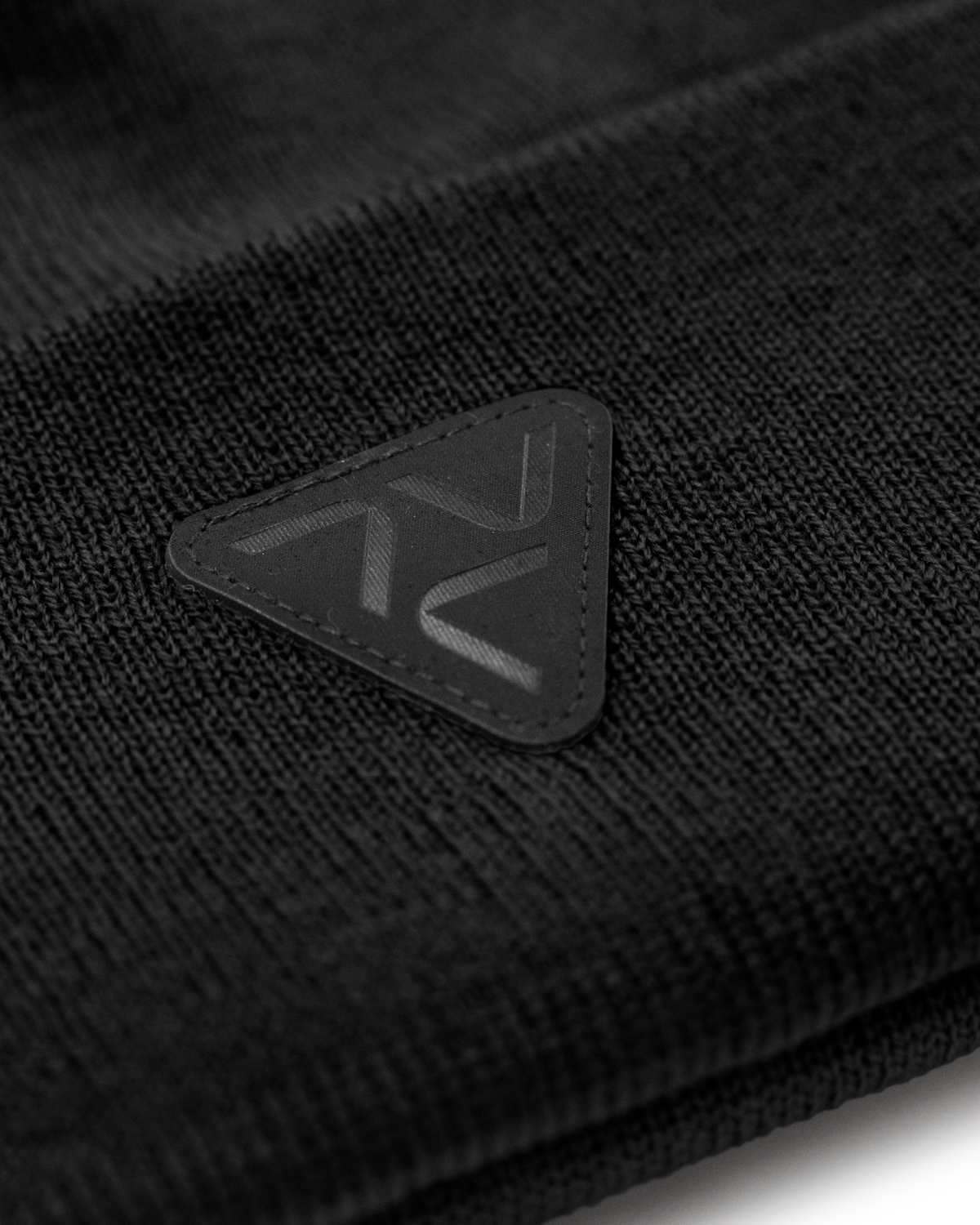 Close-up of Vohl Beanie in Black showing tonal triangular logo patch and knit texture - SKU AC-BN-900-OS | color:Black
