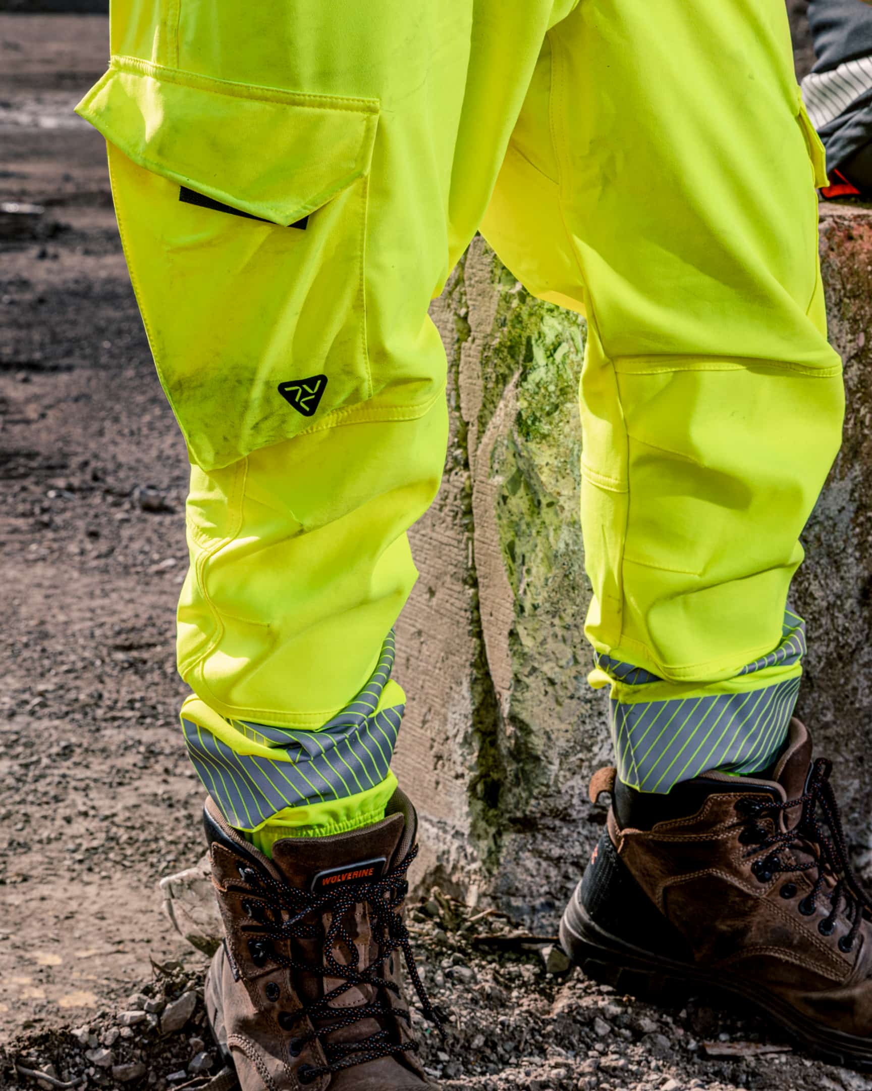 Close-up of hi-vis yellow jogger work pants with cargo pocket, reinforced knees, and reflective cuffs worn with work boots – SKU HV-JG-105 | color:Safety Yellow
