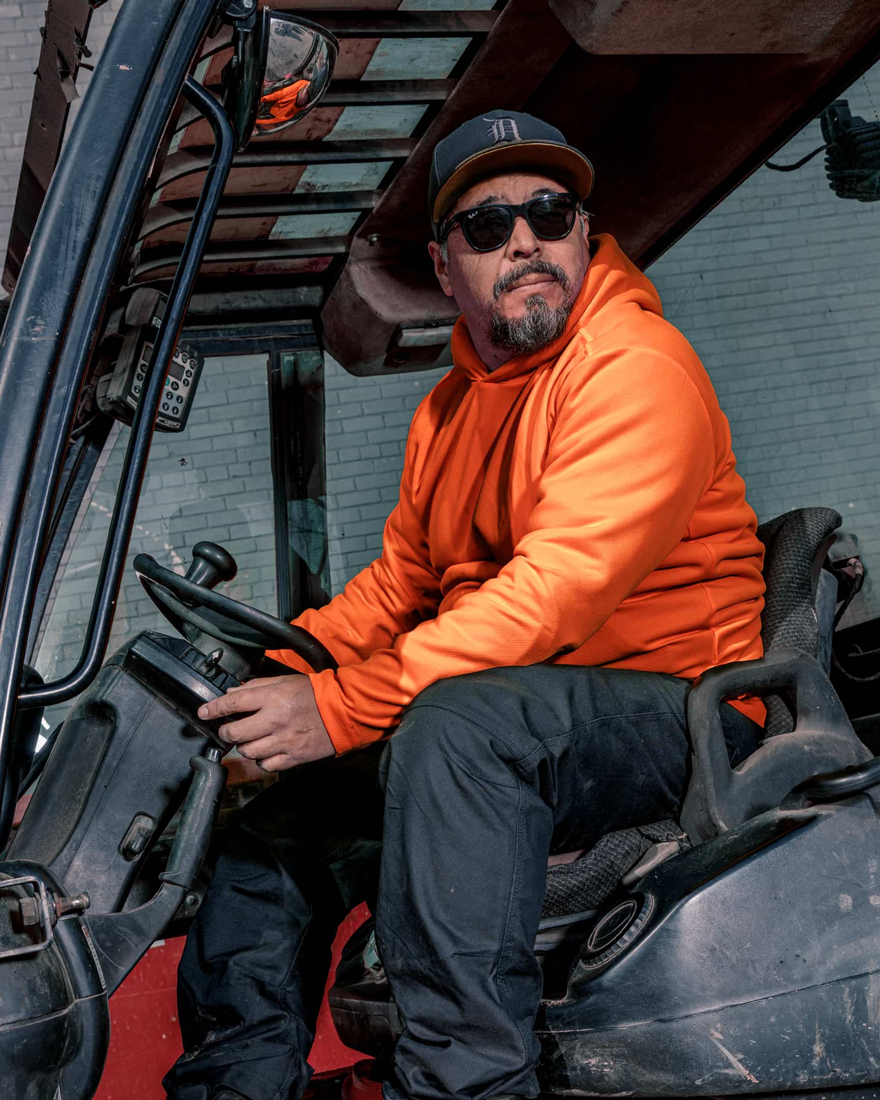 Man wearing hi-vis orange long sleeve sun hoody seated in machinery cab – SKU HV-SH-200 | color:Safety Orange